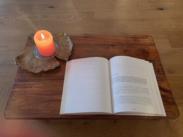 Open book with candle light on a wooden support