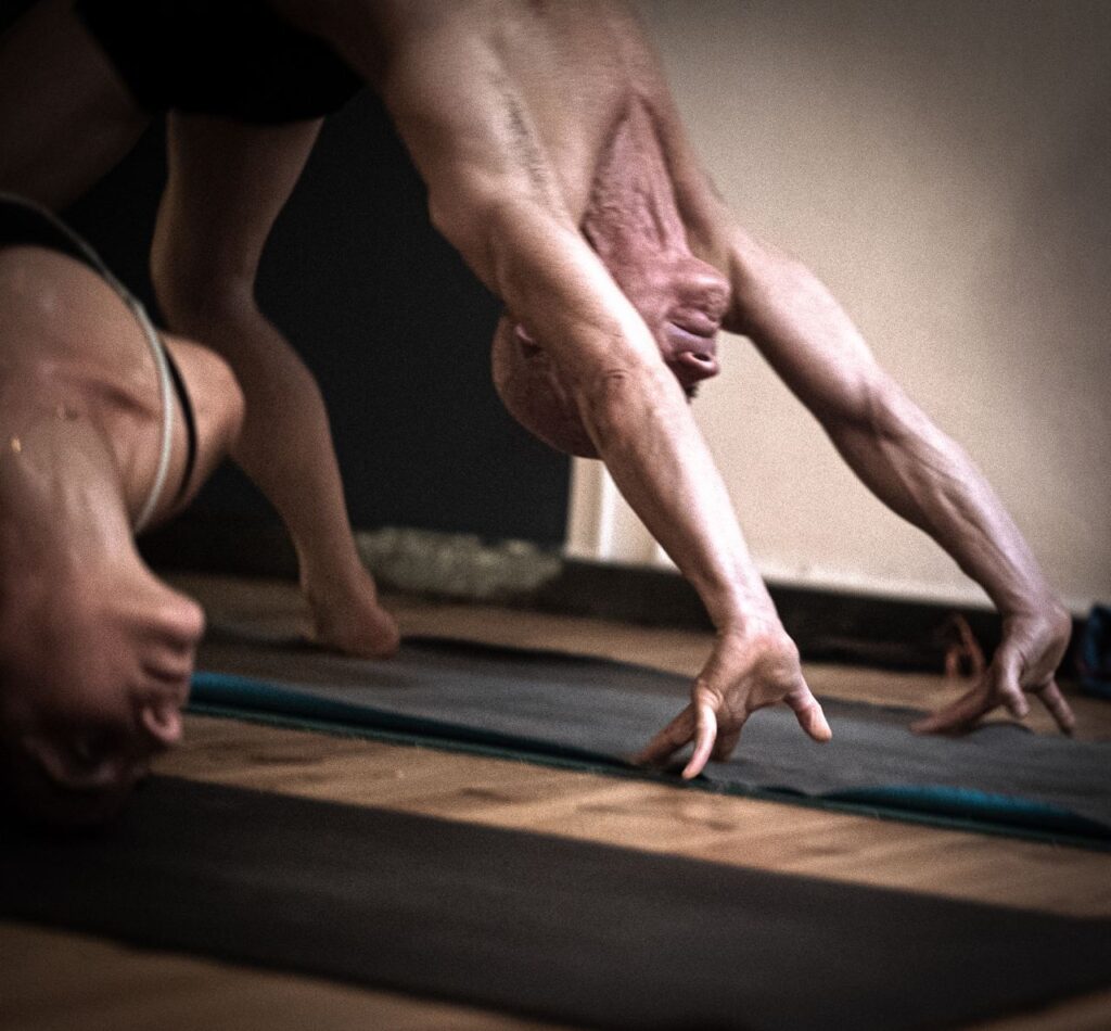 Two people participating in a yoga workshop led by Daniele Morganti, practicing Ashtanga, in Barcelona during November 2023.
